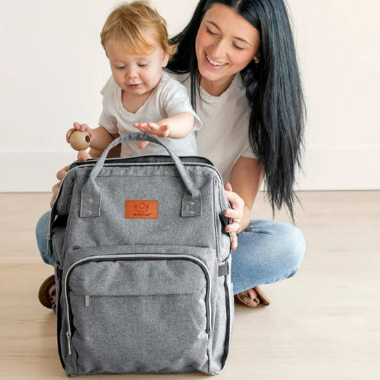 maman et bebe jouant avec sac a dos a langer